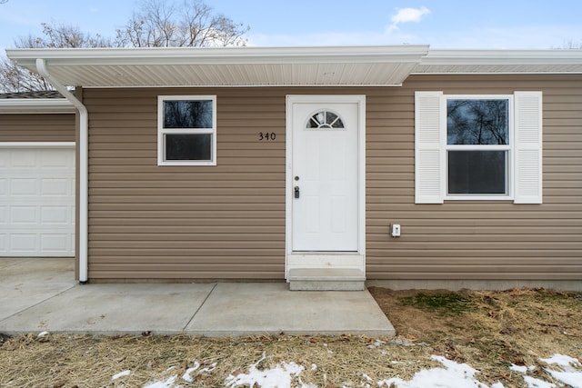 snow covered property entrance featuring a garage