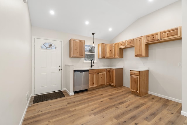 kitchen featuring sink, hanging light fixtures, stainless steel dishwasher, vaulted ceiling, and light wood-type flooring