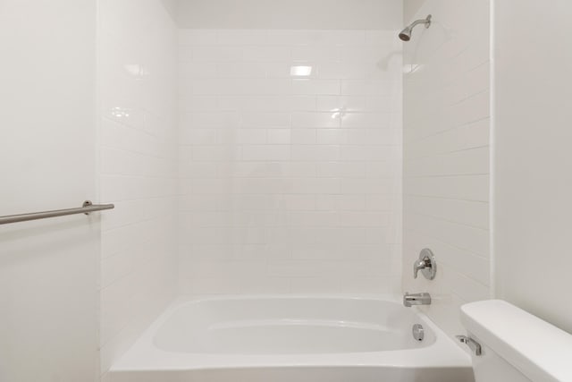 bathroom with tiled shower / bath combo and toilet