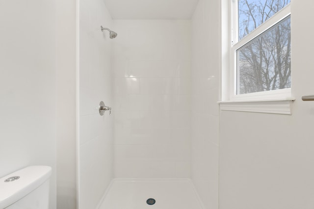 bathroom featuring tiled shower and toilet