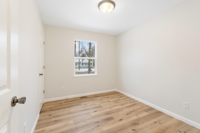 empty room featuring light wood finished floors and baseboards