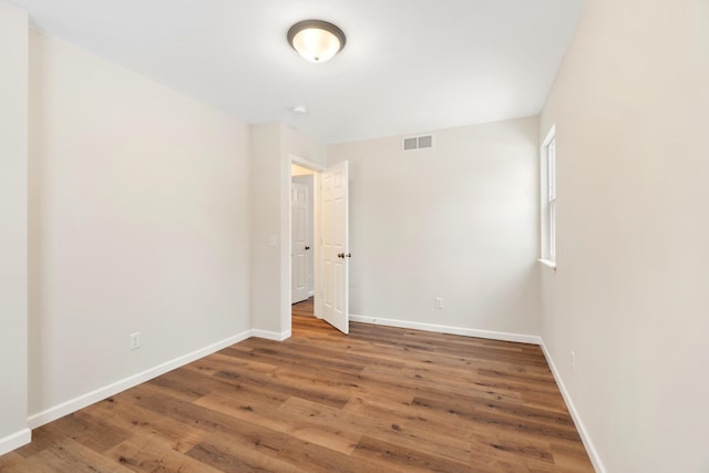 empty room featuring wood finished floors, visible vents, and baseboards