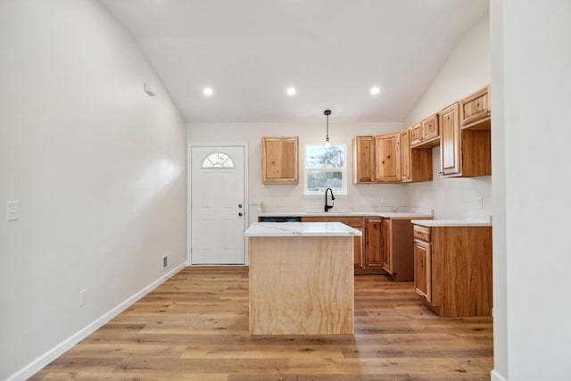 kitchen featuring baseboards, a center island, vaulted ceiling, light countertops, and light wood-style floors