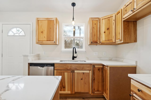 kitchen with a sink, pendant lighting, light countertops, and stainless steel dishwasher