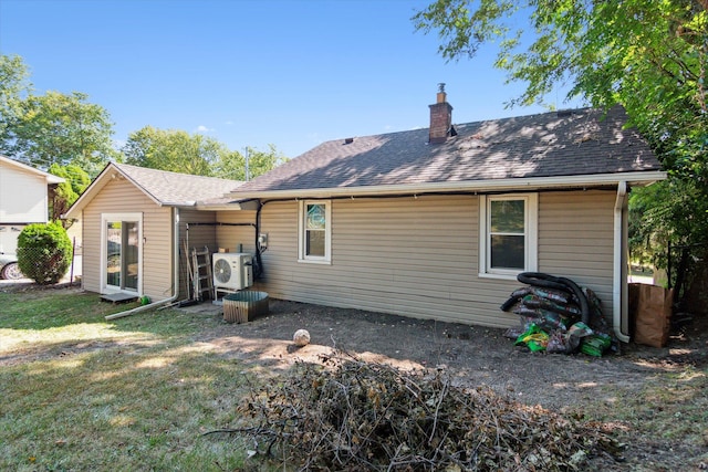 back of property with ac unit and a yard