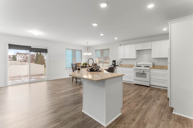 kitchen with pendant lighting, white range with gas stovetop, sink, hardwood / wood-style flooring, and white cabinetry