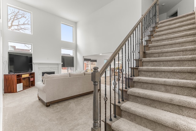 staircase with carpet flooring, a high ceiling, and a brick fireplace