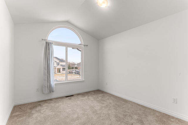 carpeted empty room with vaulted ceiling