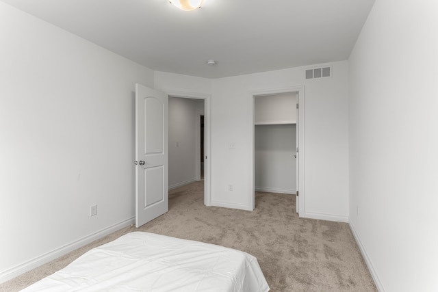 bedroom featuring light carpet, a walk in closet, and a closet