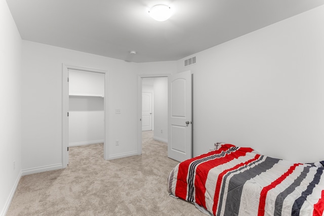 carpeted bedroom featuring a walk in closet