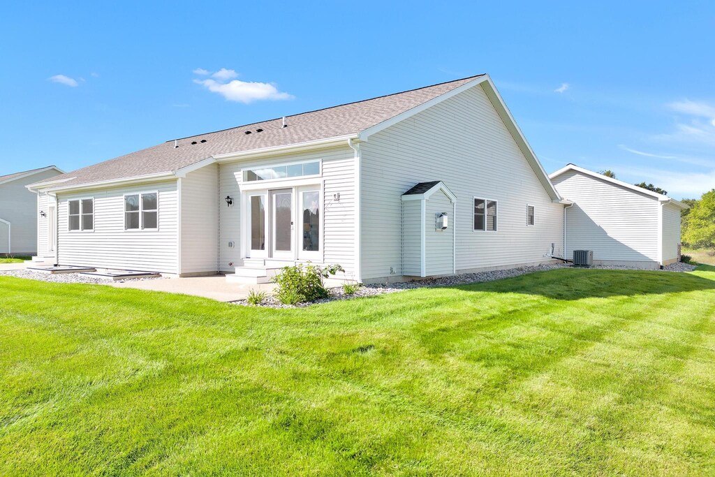 rear view of house with a lawn and central air condition unit