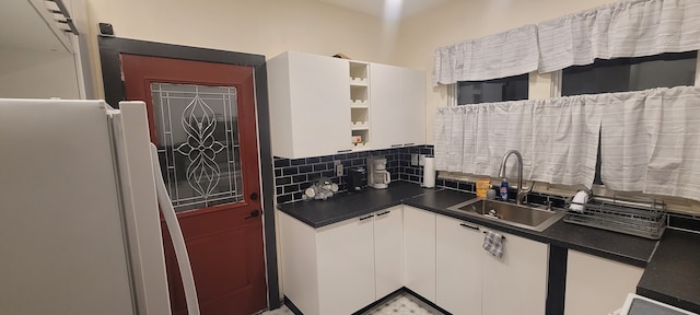 kitchen featuring white refrigerator, backsplash, white cabinetry, and sink