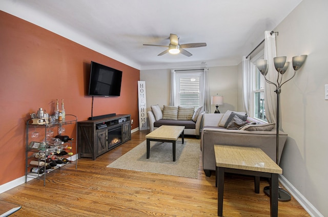 living room featuring ceiling fan, hardwood / wood-style floors, and a fireplace