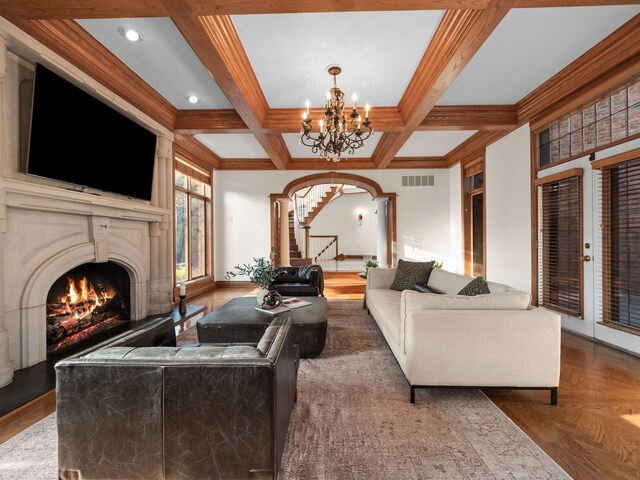 living room with parquet floors, coffered ceiling, a chandelier, crown molding, and beam ceiling