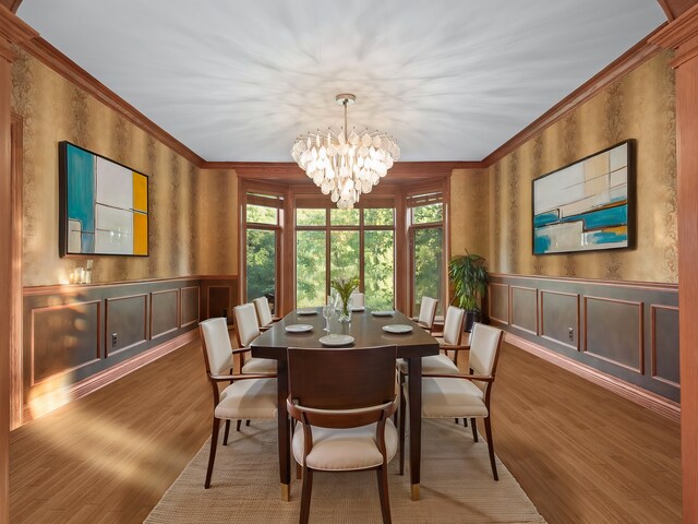 dining area with hardwood / wood-style flooring, crown molding, and a chandelier