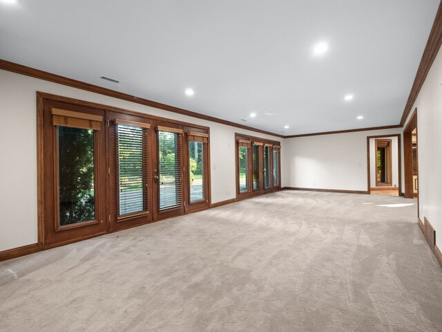 unfurnished living room featuring french doors, crown molding, and light colored carpet