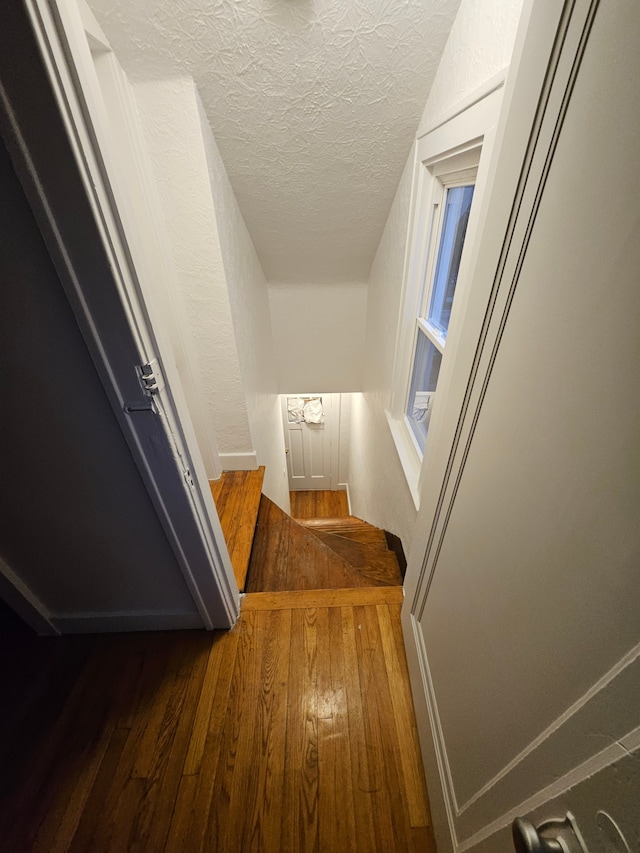 corridor with dark wood-type flooring and a textured ceiling