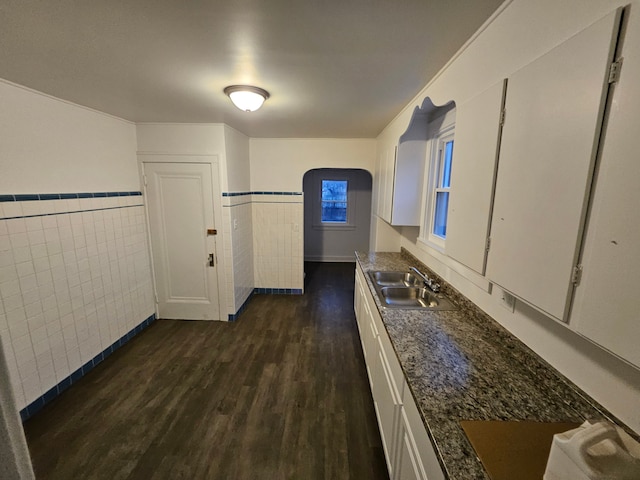 corridor with tile walls, dark wood-type flooring, and sink