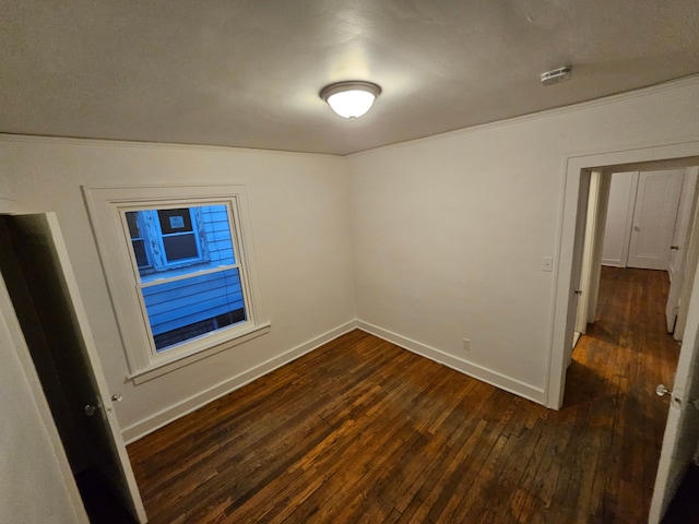 empty room with dark wood-type flooring and ornamental molding