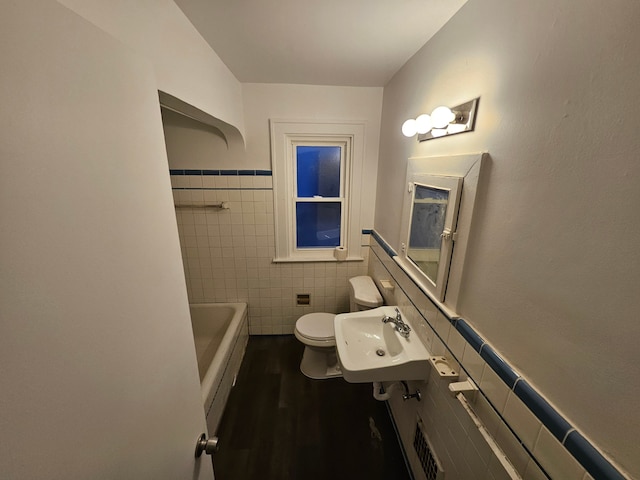 bathroom featuring toilet, tile walls, a tub to relax in, wood-type flooring, and sink