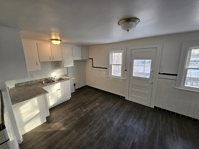 kitchen featuring white cabinets, tile walls, and sink