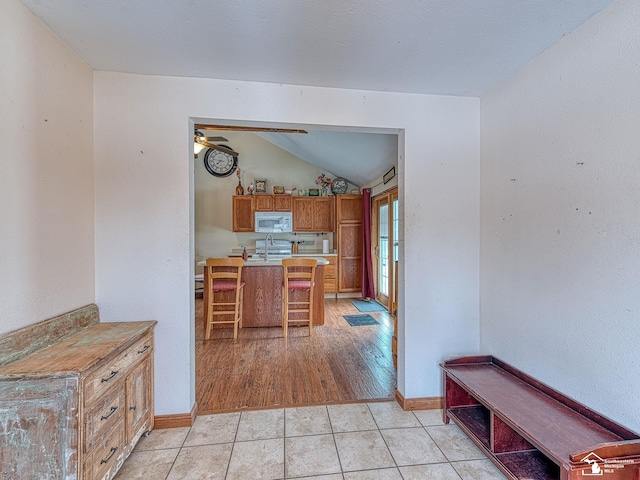 kitchen featuring kitchen peninsula, vaulted ceiling, ceiling fan, light tile patterned floors, and range