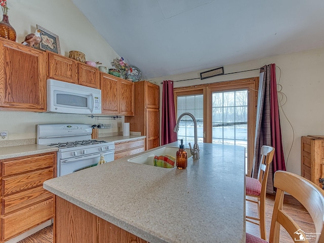 kitchen featuring white appliances, sink, a kitchen island with sink, and vaulted ceiling