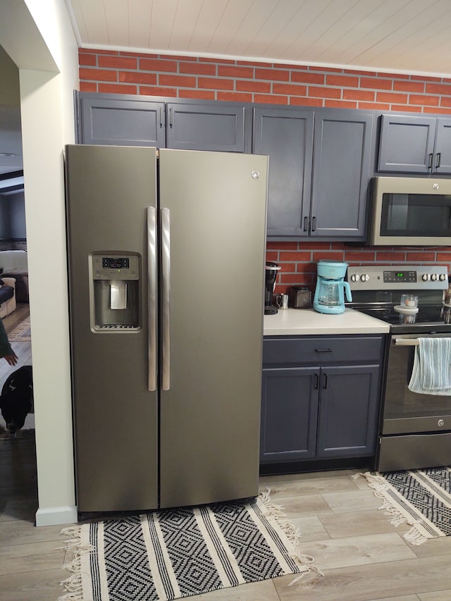 kitchen with gray cabinetry, light hardwood / wood-style floors, ornamental molding, and appliances with stainless steel finishes