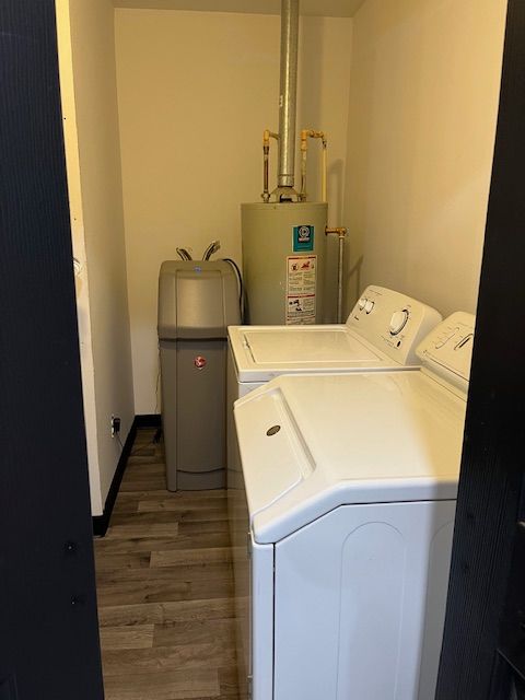 laundry room with water heater, dark hardwood / wood-style floors, and independent washer and dryer