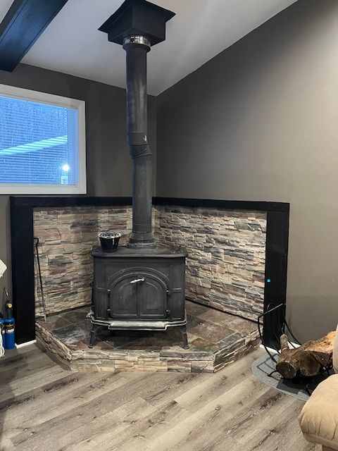 details with a wood stove, beamed ceiling, and wood-type flooring