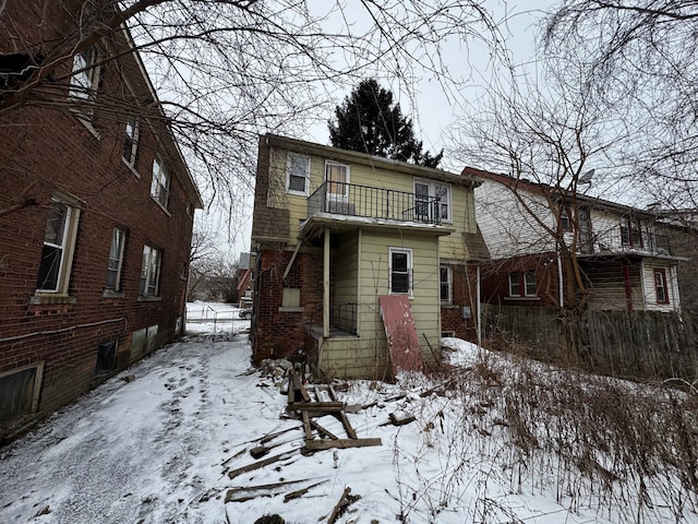 snow covered back of property with a balcony