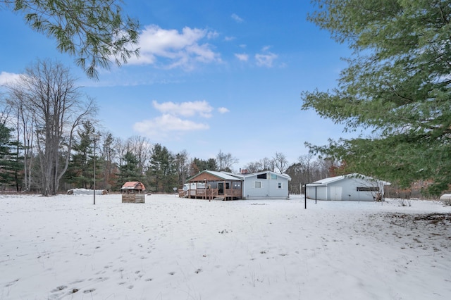 yard layered in snow featuring an outbuilding and a wooden deck