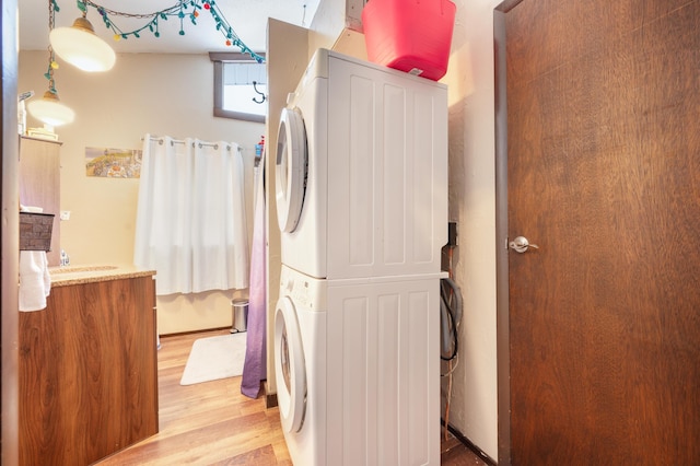 clothes washing area featuring light wood-type flooring and stacked washer / dryer