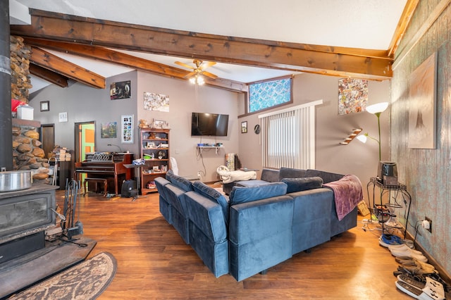 living room featuring a wood stove, ceiling fan, beamed ceiling, high vaulted ceiling, and wood-type flooring