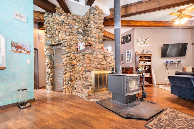 living room featuring a wood stove, high vaulted ceiling, hardwood / wood-style flooring, ceiling fan, and beamed ceiling