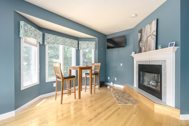 dining area featuring a tiled fireplace and hardwood / wood-style floors