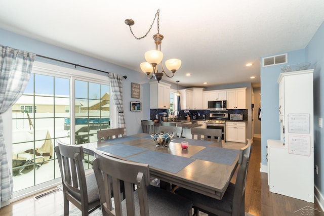 dining area with dark wood-type flooring, sink, and a chandelier