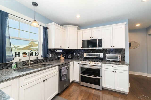 kitchen with white cabinets, appliances with stainless steel finishes, dark hardwood / wood-style floors, and sink