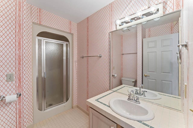 bathroom with tile patterned floors, vanity, toilet, and a shower with shower door