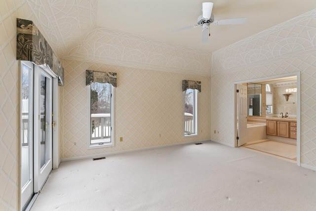 unfurnished bedroom featuring light colored carpet, ensuite bath, and ceiling fan