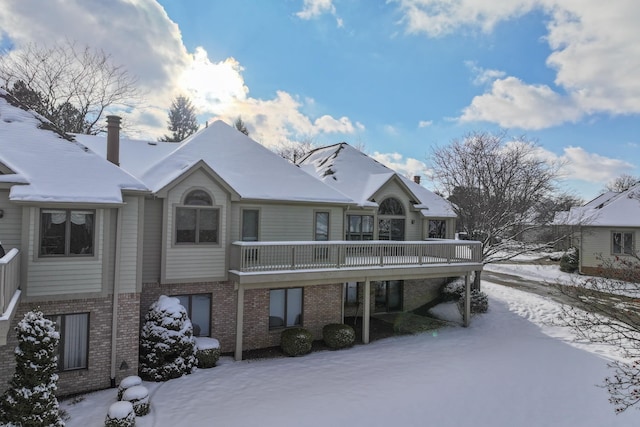 snow covered rear of property with a deck