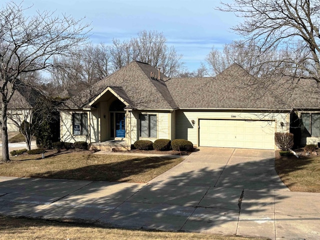 view of front of property with an attached garage, concrete driveway, and a shingled roof