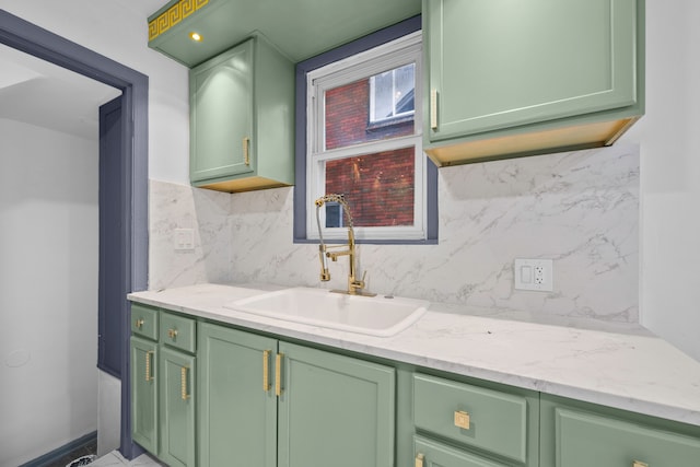 interior space featuring light stone counters, sink, green cabinetry, and tasteful backsplash