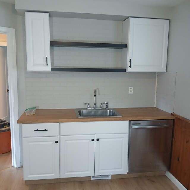 bar featuring white cabinetry, dishwasher, sink, backsplash, and butcher block countertops