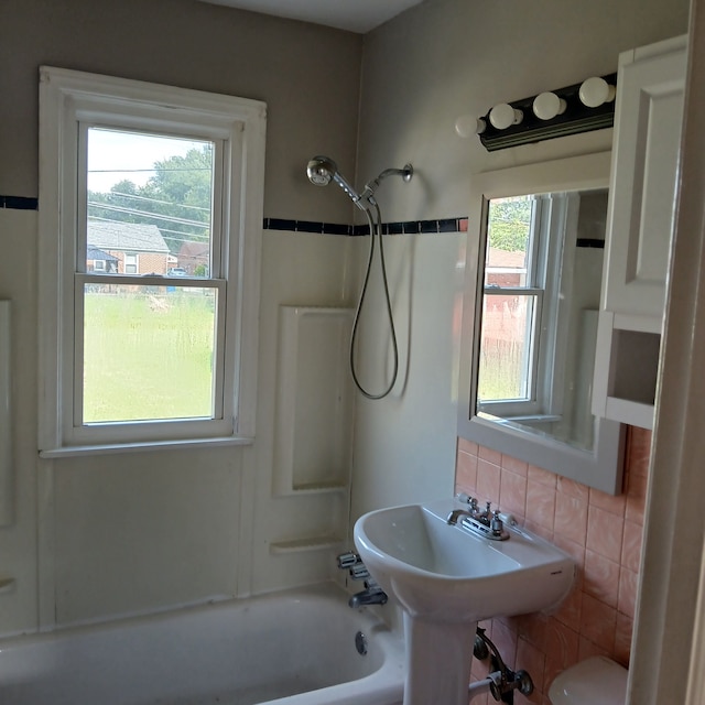 bathroom with backsplash, a wealth of natural light, and  shower combination