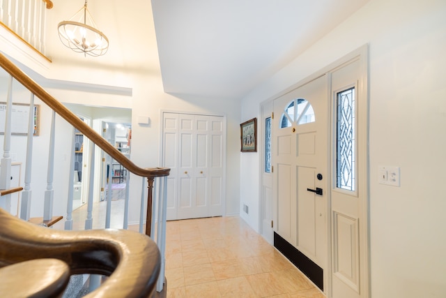 tiled entrance foyer featuring an inviting chandelier