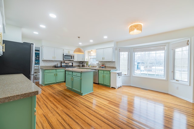 kitchen with white cabinets, a kitchen island, stainless steel appliances, and green cabinetry