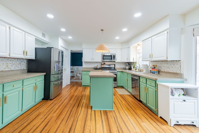 kitchen featuring white cabinets, sink, hanging light fixtures, appliances with stainless steel finishes, and a kitchen island