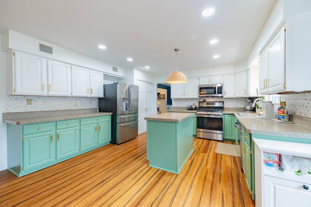 kitchen with a center island, white cabinets, sink, decorative light fixtures, and stainless steel appliances