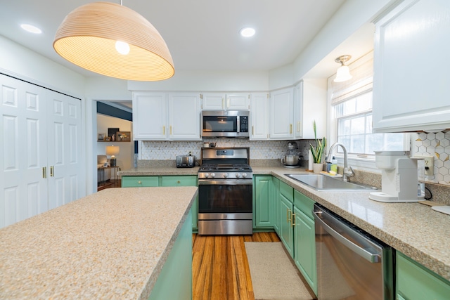 kitchen featuring decorative backsplash, stainless steel appliances, sink, green cabinetry, and white cabinetry